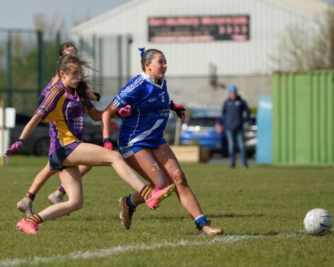Kilmacud player kicking the ball low along the ground